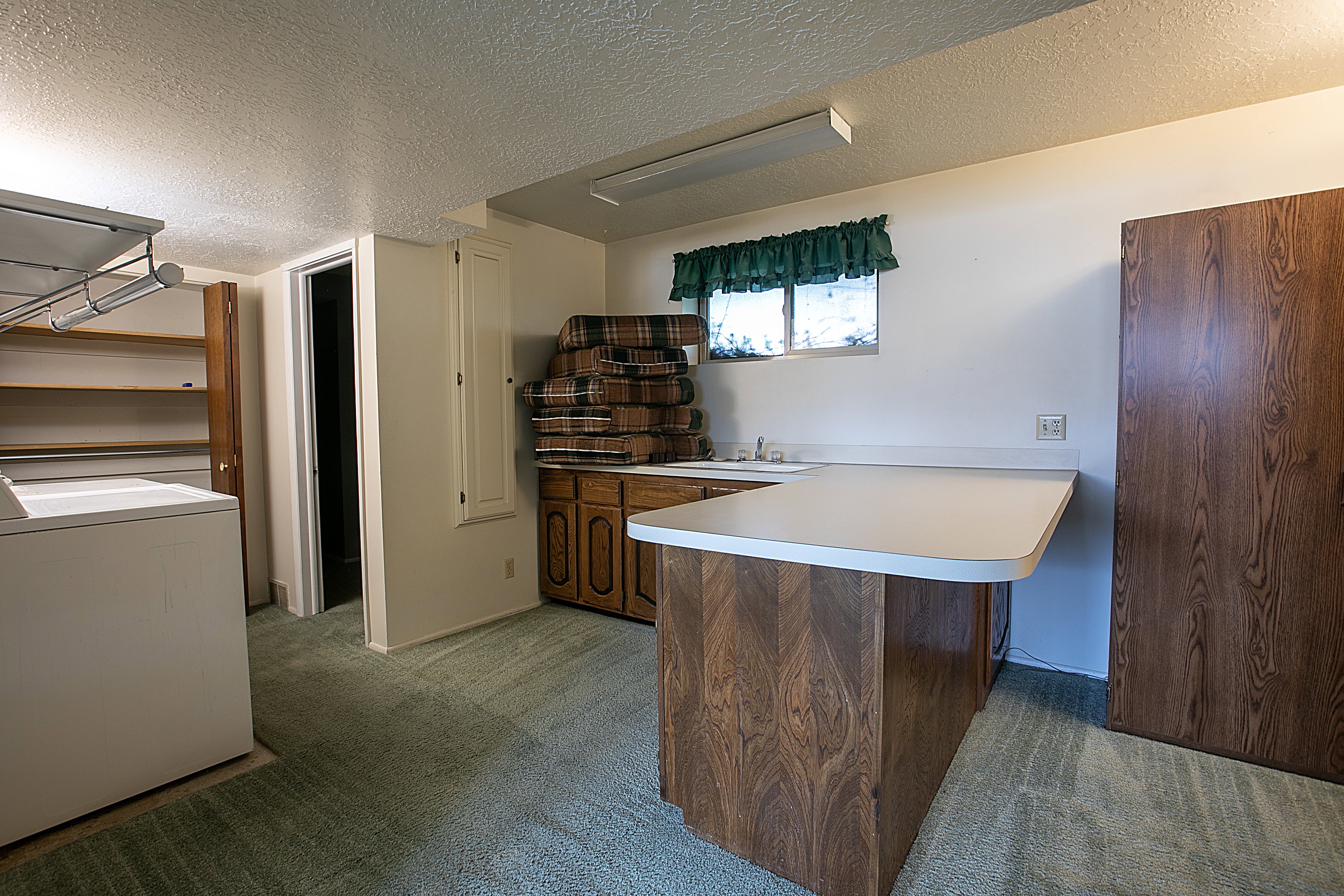 Kitchen with a peninsula, light colored carpet, a textured ceiling, light countertops, and wood finish cabinets