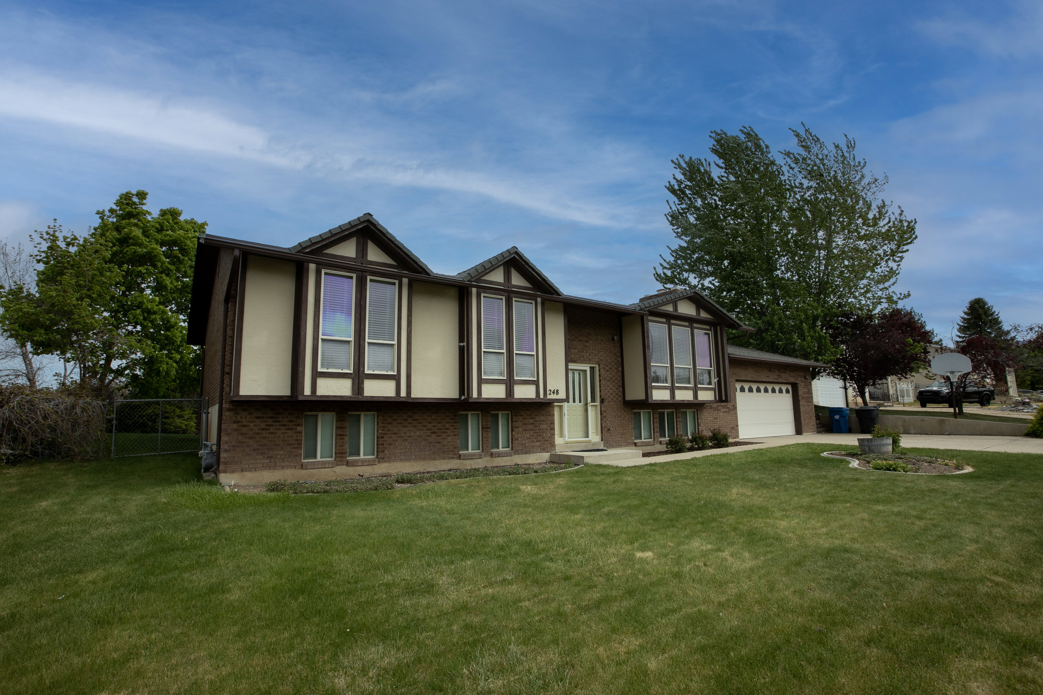 View of front of home featuring brick siding, a front lawn, an attached garage, and driveway
