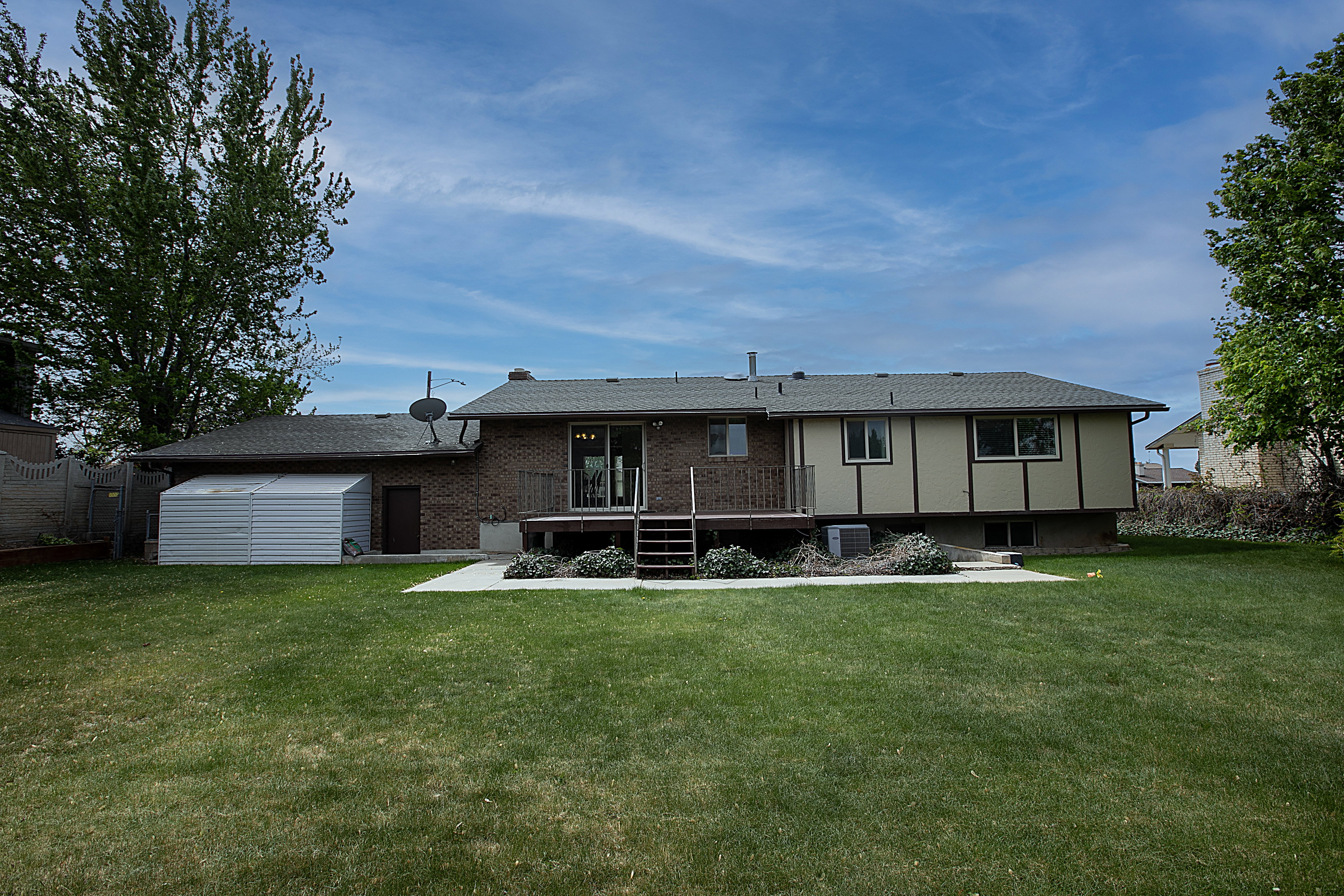 Rear view of house featuring a storage shed and brick siding
