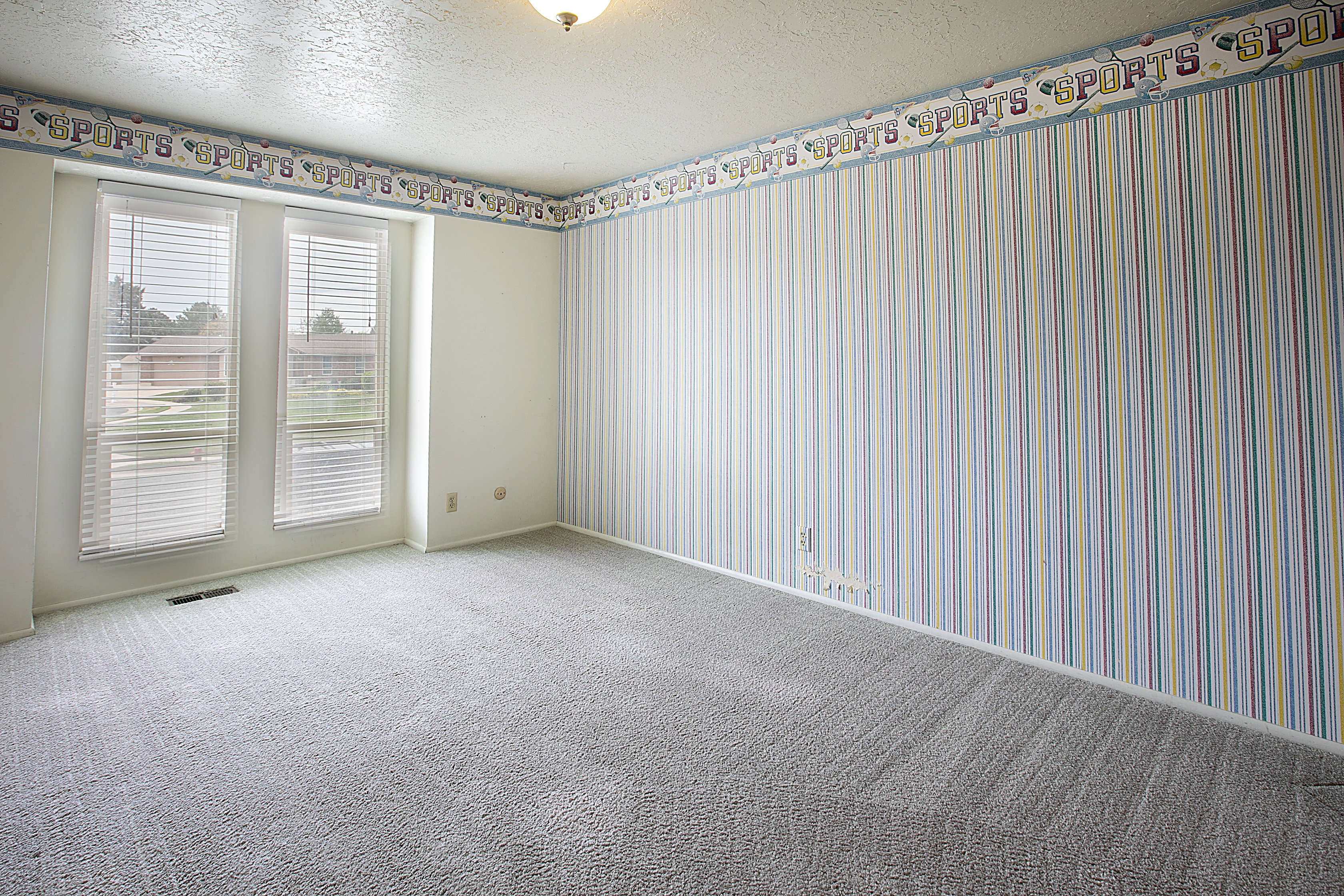 Carpeted empty room with a textured ceiling and wallpapered walls