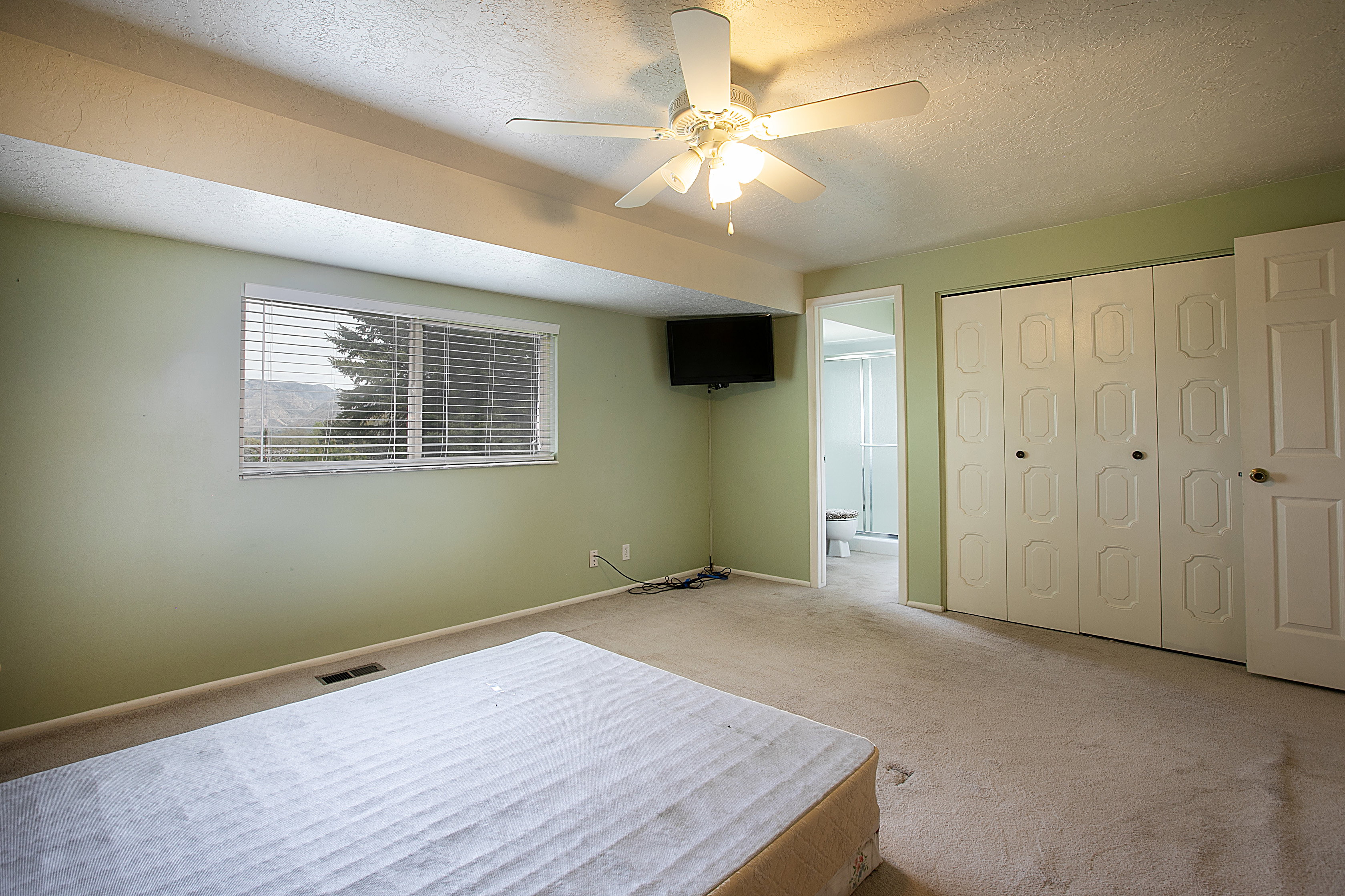 Carpeted bedroom with a textured ceiling, a ceiling fan, and ensuite bath