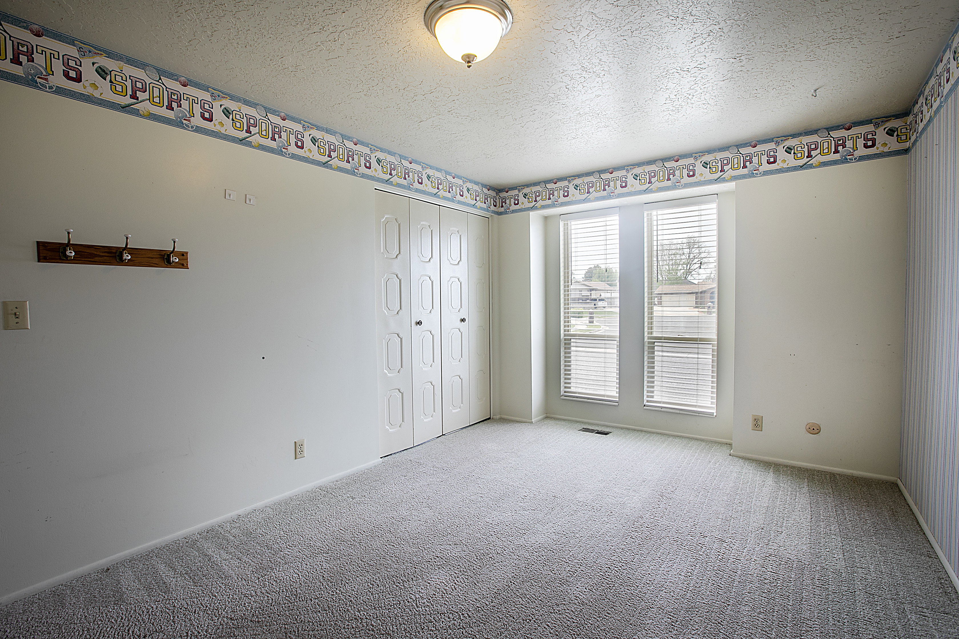 Carpeted empty room with a textured ceiling and baseboards