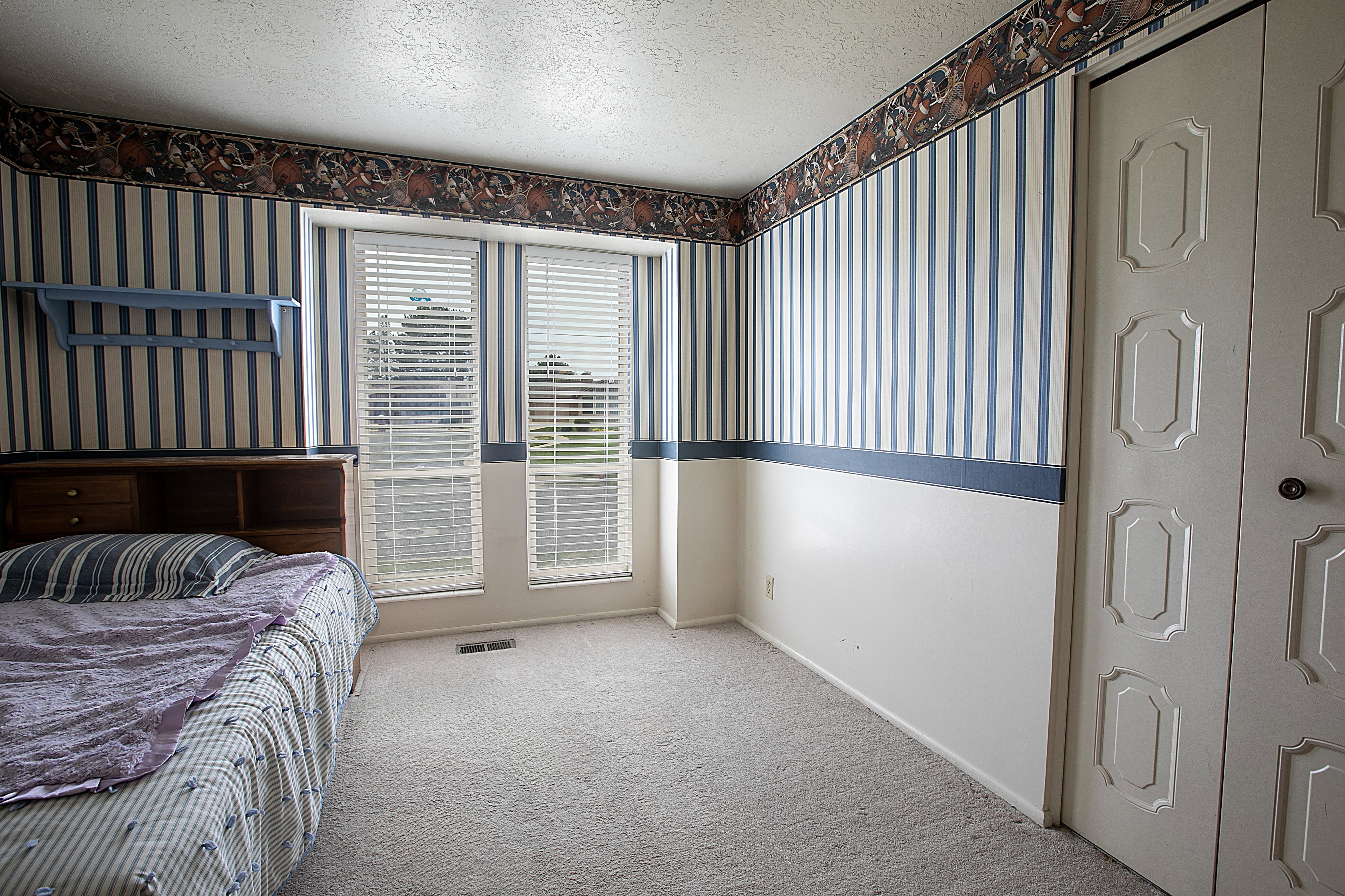 Bedroom with wallpapered walls, a textured ceiling, and carpet