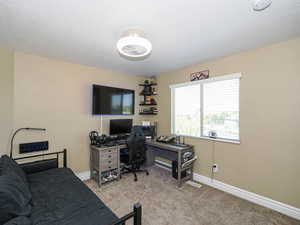Bedroom featuring light carpet, an office area, and a textured ceiling