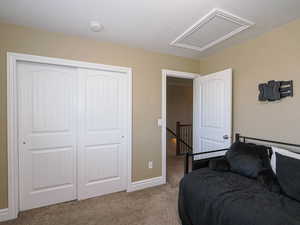 Bedroom with light colored carpet and a closet