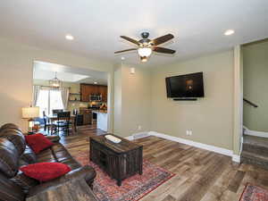 Living area featuring dark wood-style floors, hanging lights, and ceiling fan