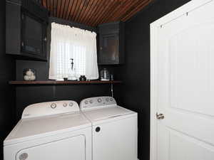 Laundry room with cabinet space, washing machine and clothes dryer, and wood ceiling