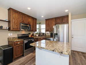 Kitchen with stainless steel appliances, light stone counters, light wood-style flooring, and recessed lighting