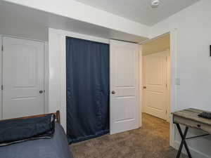 Bedroom featuring dark colored carpet and a textured ceiling
