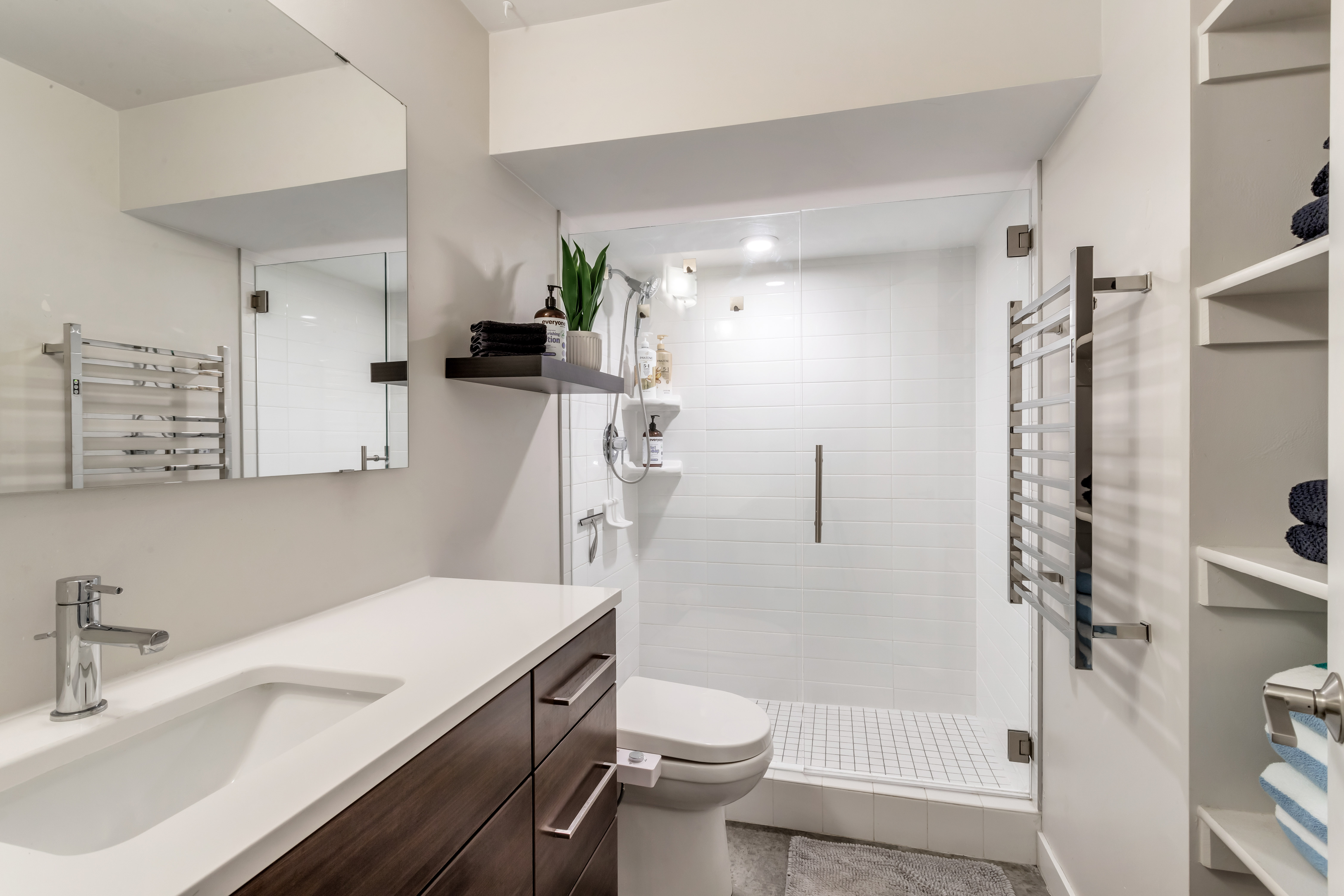 Full bath featuring a towel warming rack, vanity, a stall shower, and radiator