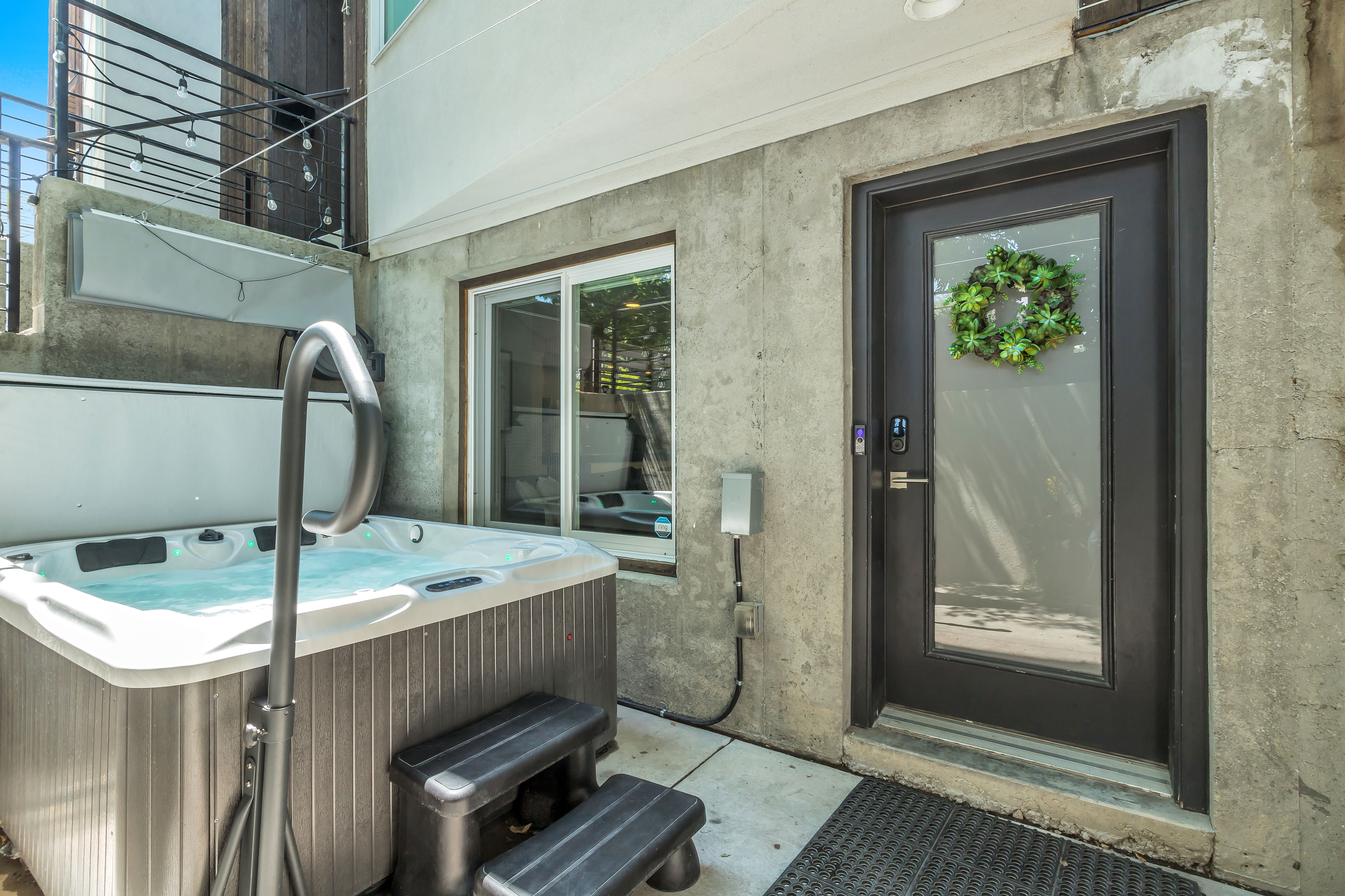 Entrance to property with a patio, a hot tub, and stucco siding
