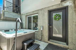 Entrance to property with a patio, a hot tub, and stucco siding