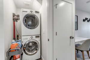 ADU Laundry room featuring stacked washer and clothes dryer and baseboards