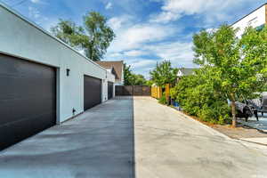 View of home's exterior with stucco siding, driveway, and a gate