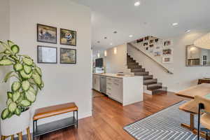 Interior space with light wood-type flooring, pendant lighting, light stone counters, white cabinets, and stainless steel appliances