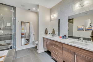 Master Bathroom featuring double vanity, a tub to relax in, dark tile patterned flooring, a stall shower, and recessed lighting