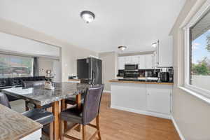 Kitchen with a peninsula, white cabinets, stainless steel appliances, open floor plan, and light wood-type flooring
