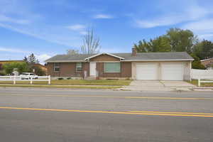 Single story home with concrete driveway, an attached garage, a chimney, brick siding, and a shingled roof