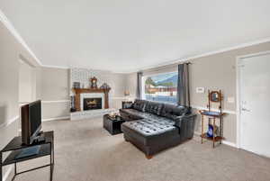Living room featuring a fireplace, light colored carpet, and crown molding