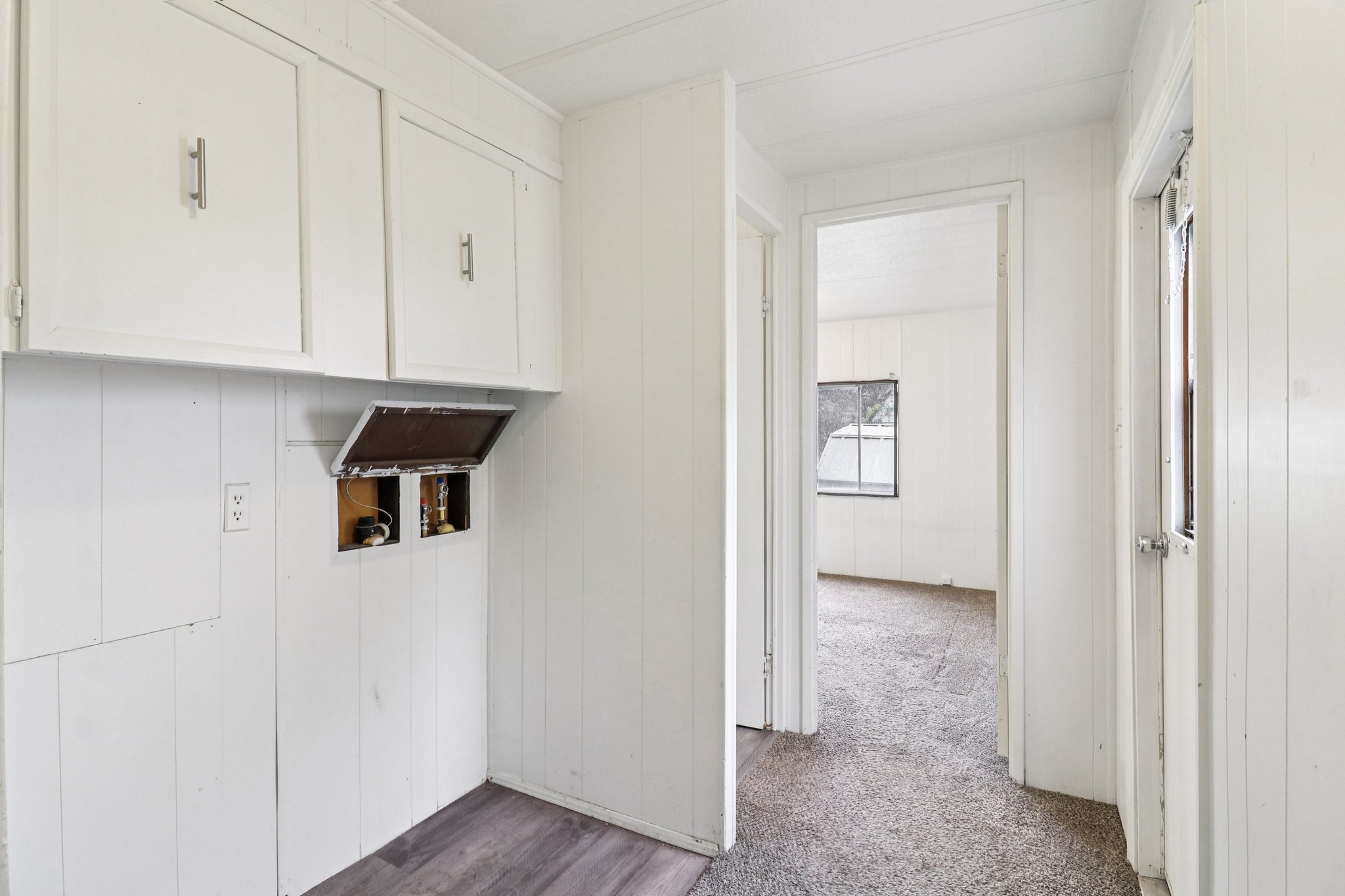 Laundry area with washer hookup, cabinet space, wooden walls, dark carpet, and dark wood-style floors