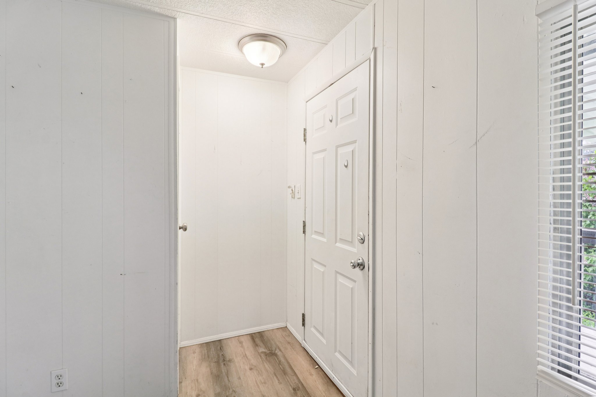 Hall featuring wood walls, light wood finished floors, and a textured ceiling