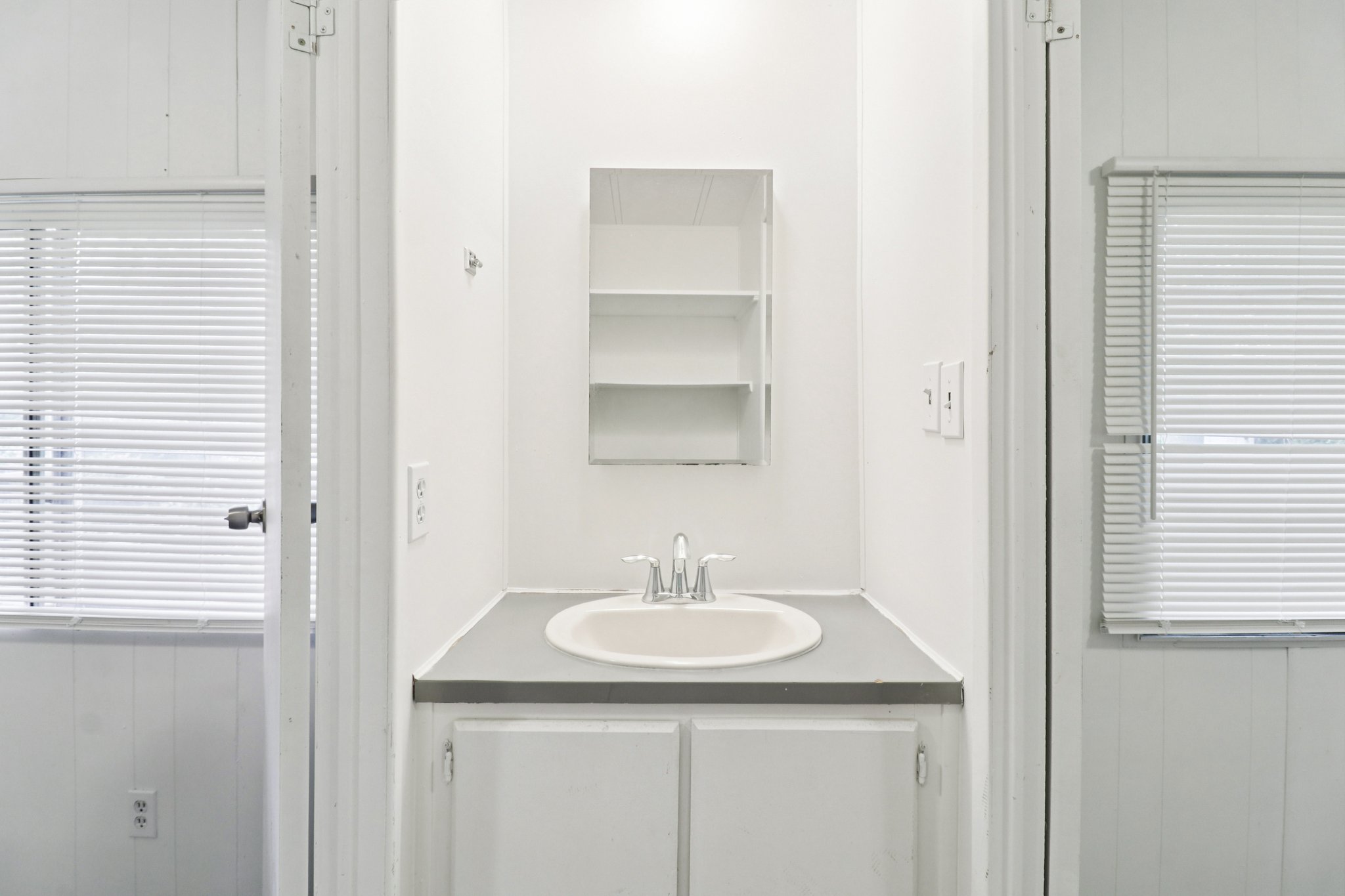 Bathroom with wood walls, vanity, wainscoting, and a decorative wall