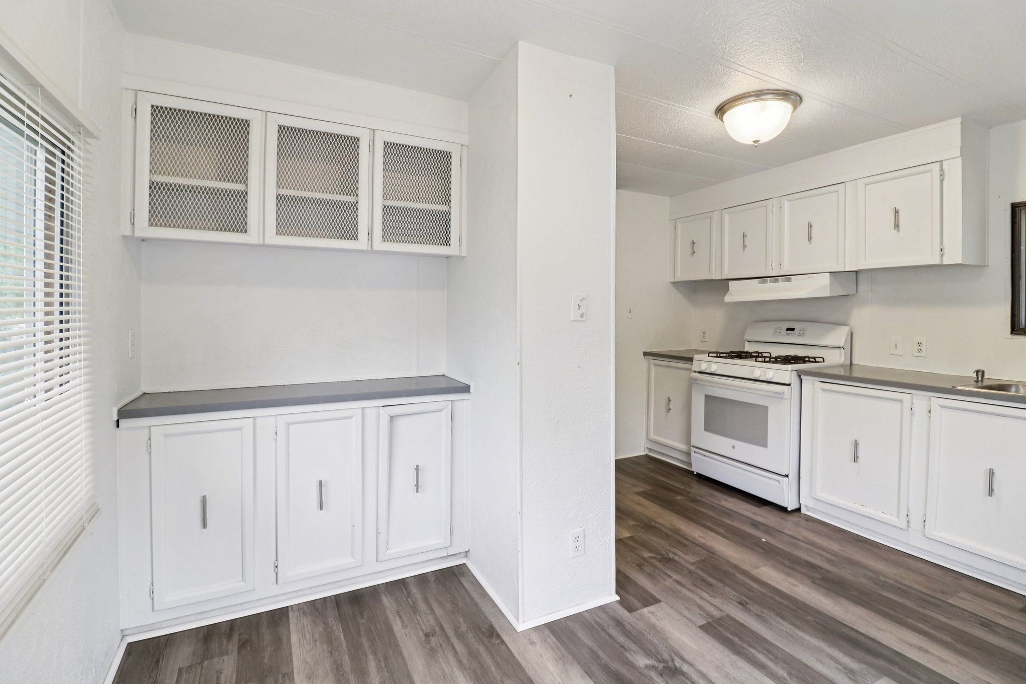Kitchen featuring white cabinetry, gas range gas stove, dark wood-style floors, glass fronted cabinets, and healthy amount of natural light