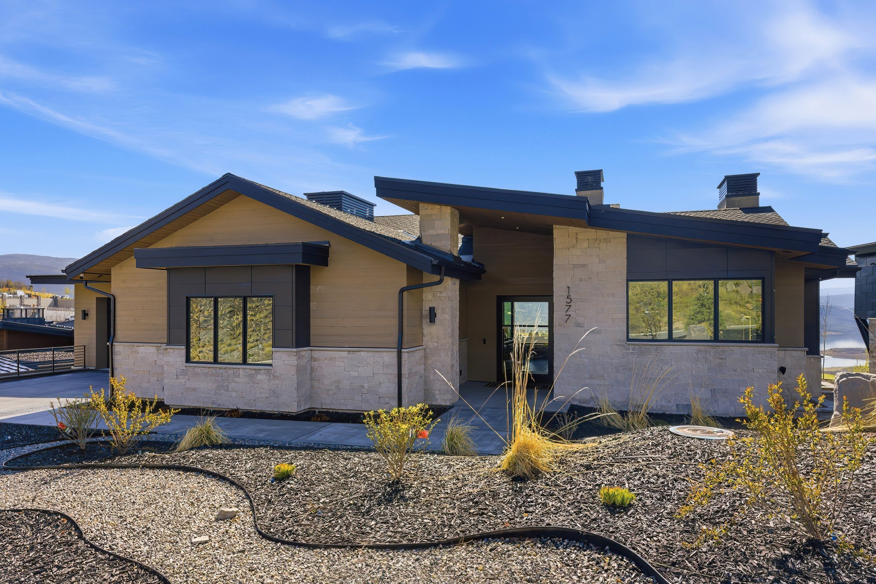 Contemporary house with a chimney, stone siding, and a garage