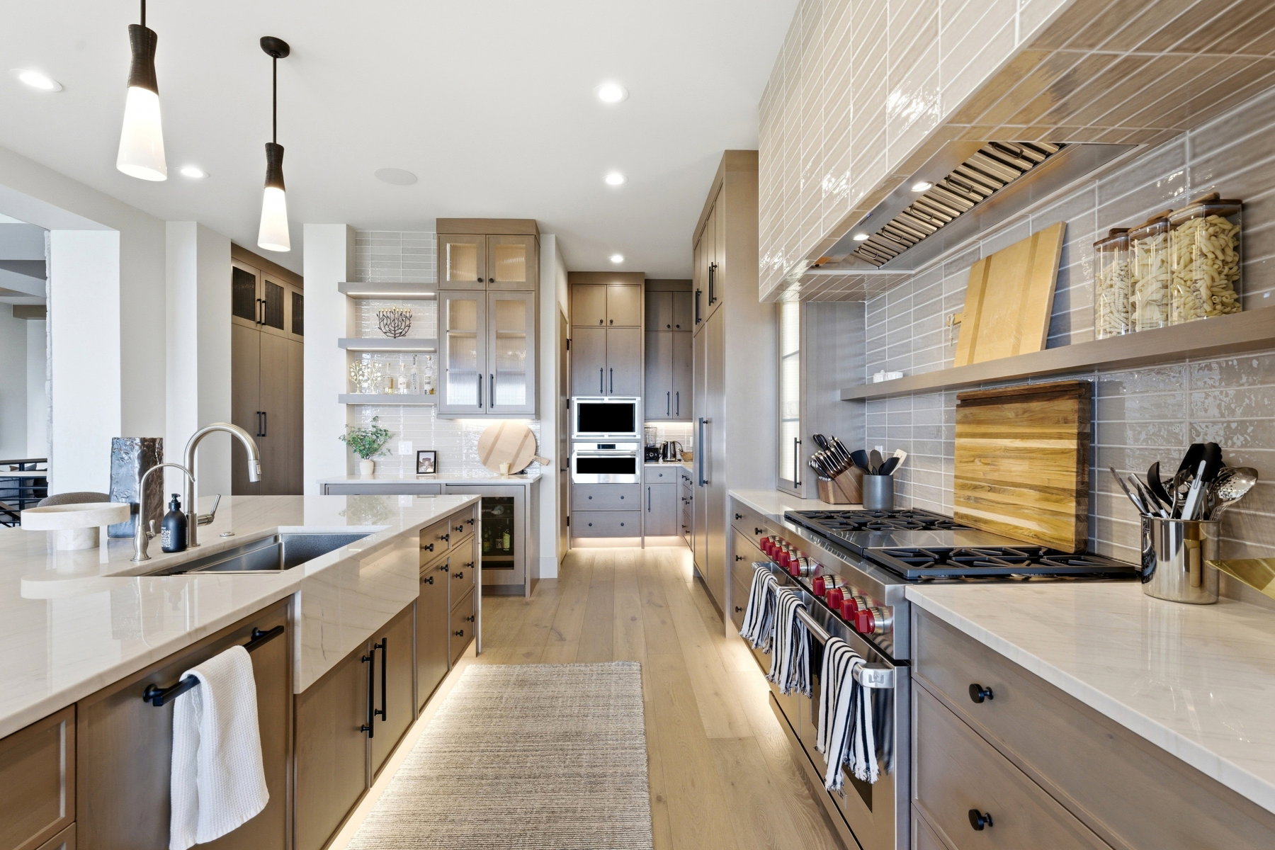 Dual tone kitchen featuring open shelves, stainless steel appliances, pendant lighting, light stone counters, and light wood-style flooring
