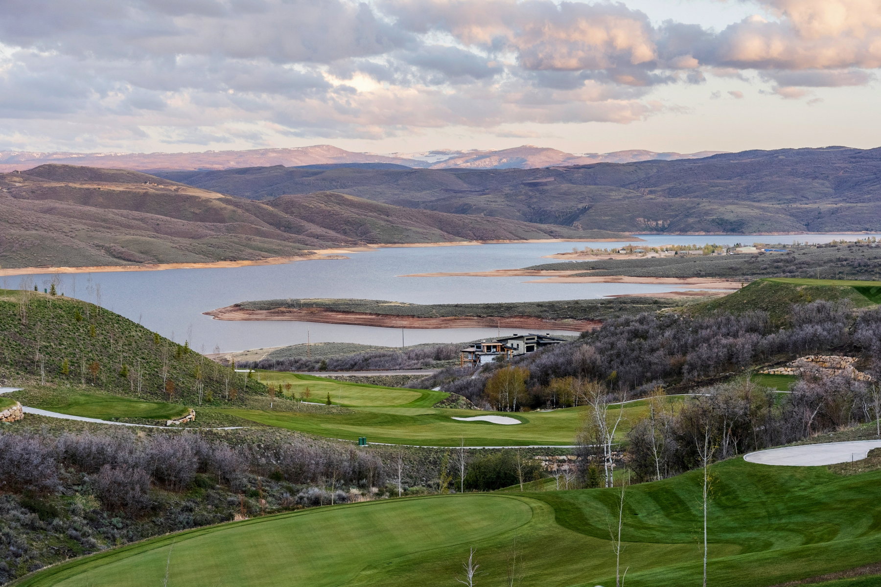 View of mountain backdrop with a nearby body of water and a golf course