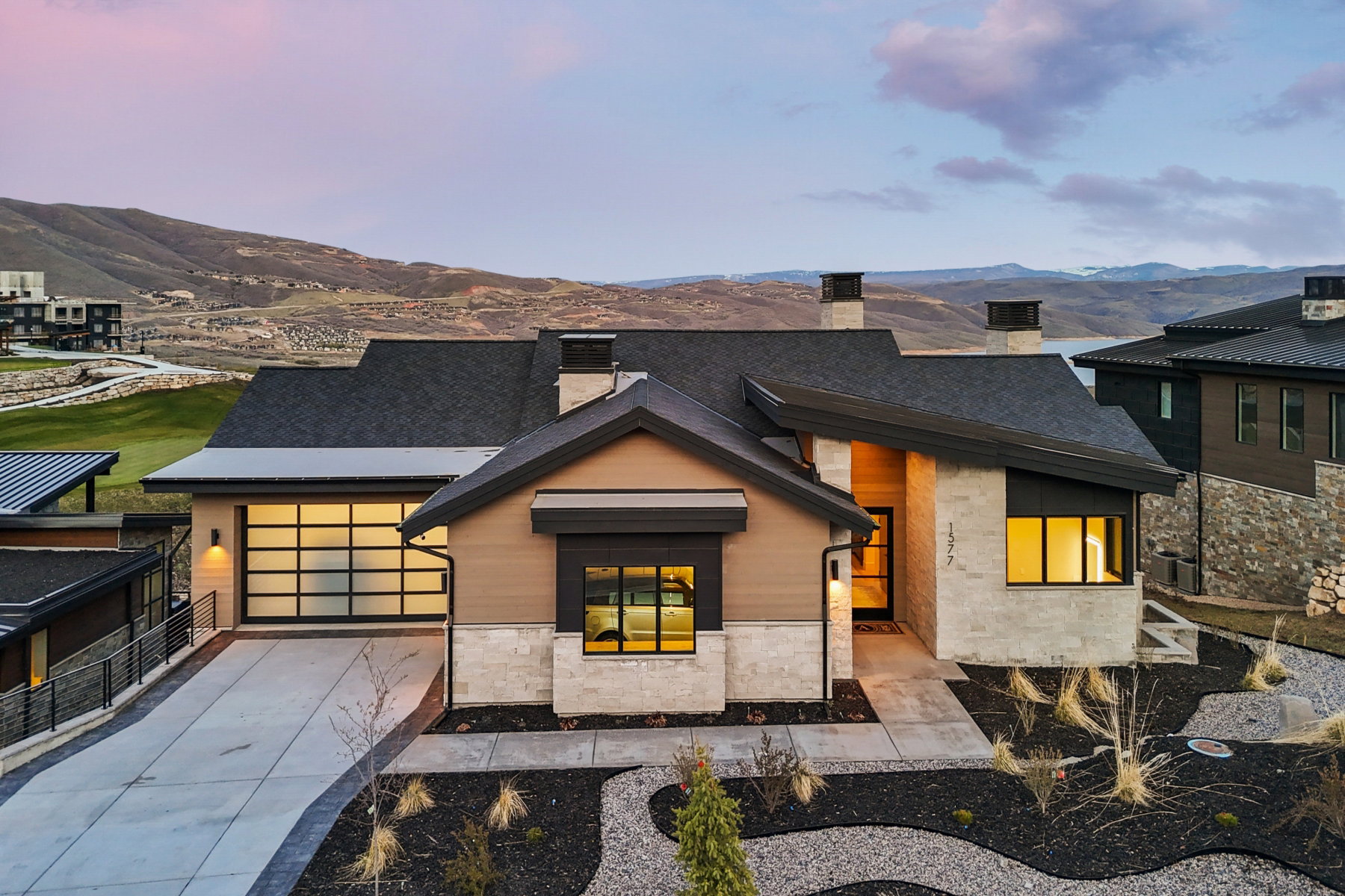 View of front of property with stone siding, a chimney, concrete driveway, a garage, and a mountain view