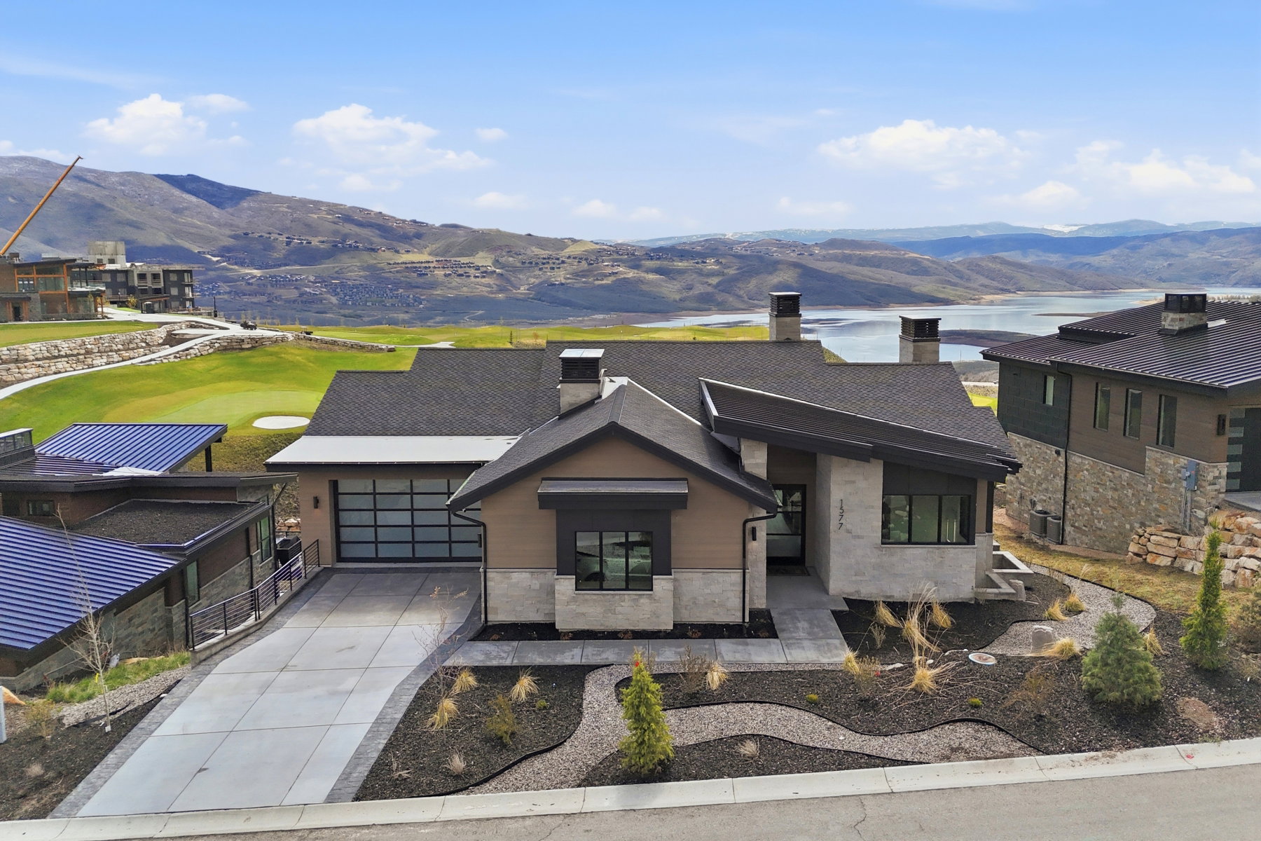 Contemporary home featuring a chimney, a mountain view, driveway, stucco siding, and stone siding