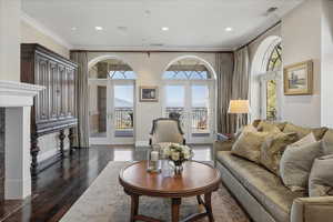 Living room featuring french doors, ornamental molding, dark wood finished floors, recessed lighting, and a premium fireplace