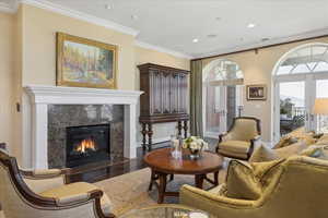 Living area featuring french doors, ornamental molding, a fireplace, wood finished floors, and recessed lighting
