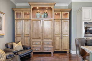 Sitting room featuring dark wood-type flooring and crown molding