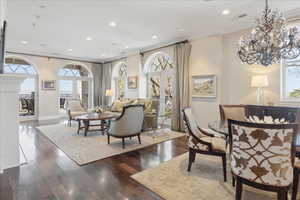 Living room featuring dark wood finished floors, recessed lighting, crown molding, and french doors
