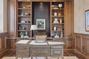Home office featuring a wainscoted wall, wallpapered walls, a decorative wall, and dark wood-style floors