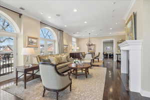 Living room with ornamental molding, dark wood-style floors, a fireplace, and a chandelier
