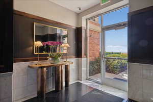 Doorway to outside featuring tile walls, a wainscoted wall, and tile patterned flooring