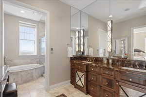 Ensuite bathroom featuring double vanity, a bath, and recessed lighting