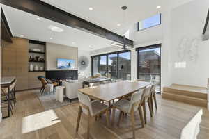 Dining space with light wood-type flooring, a ceiling fan, healthy amount of natural light, recessed lighting, and a high ceiling