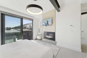 Bedroom featuring beamed ceiling, light carpet, and a multi sided fireplace