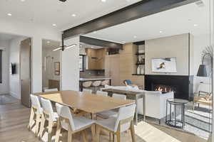 Dining area featuring light wood-type flooring, recessed lighting, and a large fireplace