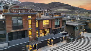 View of front of home with a mountain view, a garage, a metal roof, a residential view, and driveway