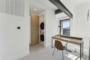 Office space featuring light colored carpet and stacked washer and clothes dryer