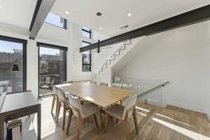Dining space with light wood-type flooring, a high ceiling, and recessed lighting