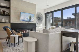 Living room with a glass covered fireplace, wood finished floors, and recessed lighting
