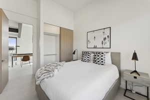 Bedroom with a desk, light carpet, and a closet