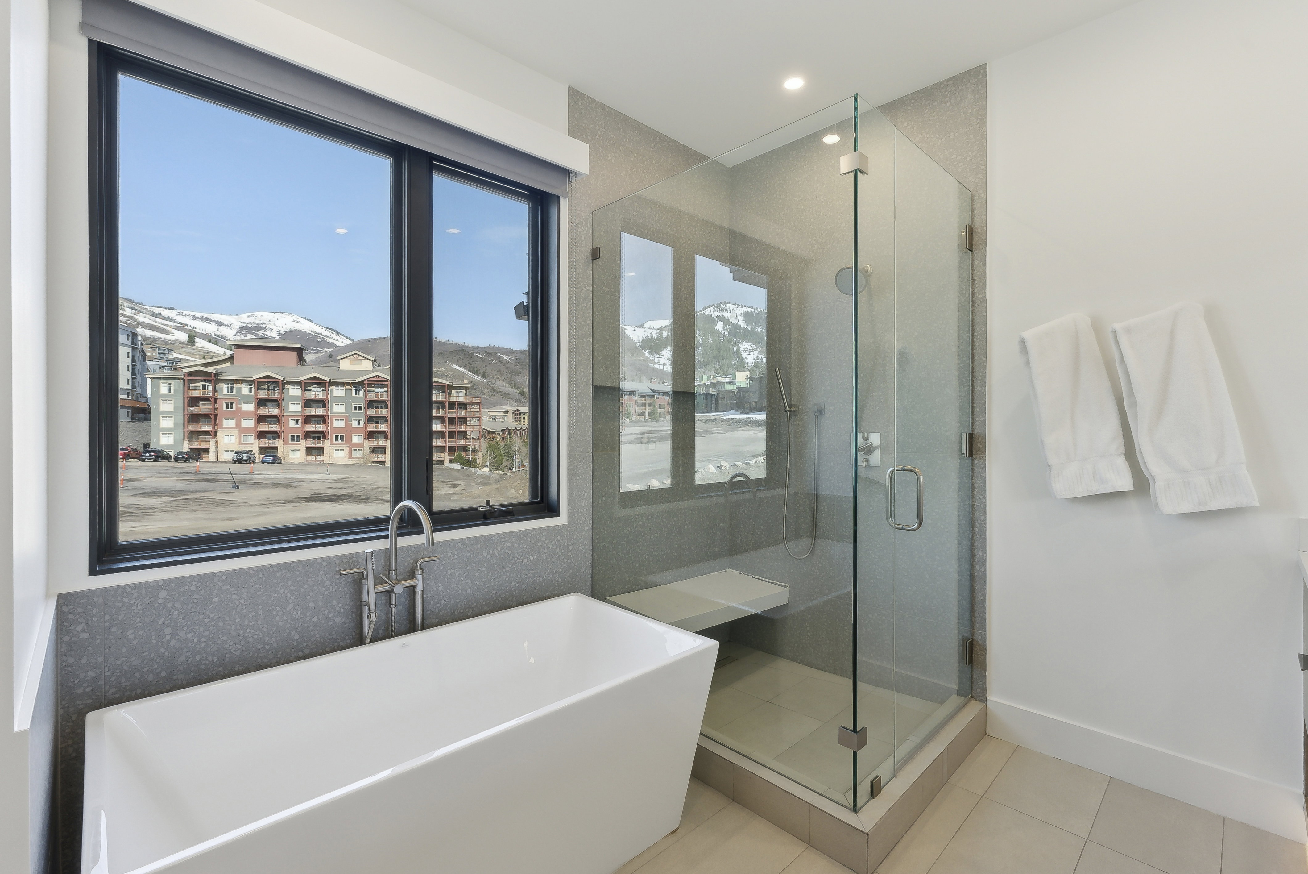 Bathroom with a freestanding bath, a stall shower, light tile patterned floors, a mountain view, and recessed lighting