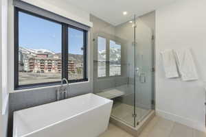 Bathroom with a freestanding bath, a stall shower, light tile patterned floors, a mountain view, and recessed lighting